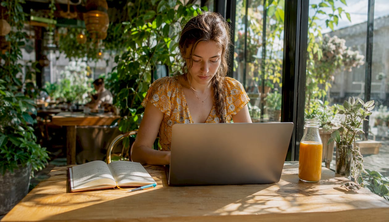 Im Café sitzt eine Reisebloggerin und arbeitet konzentriert an ihrem Laptop.