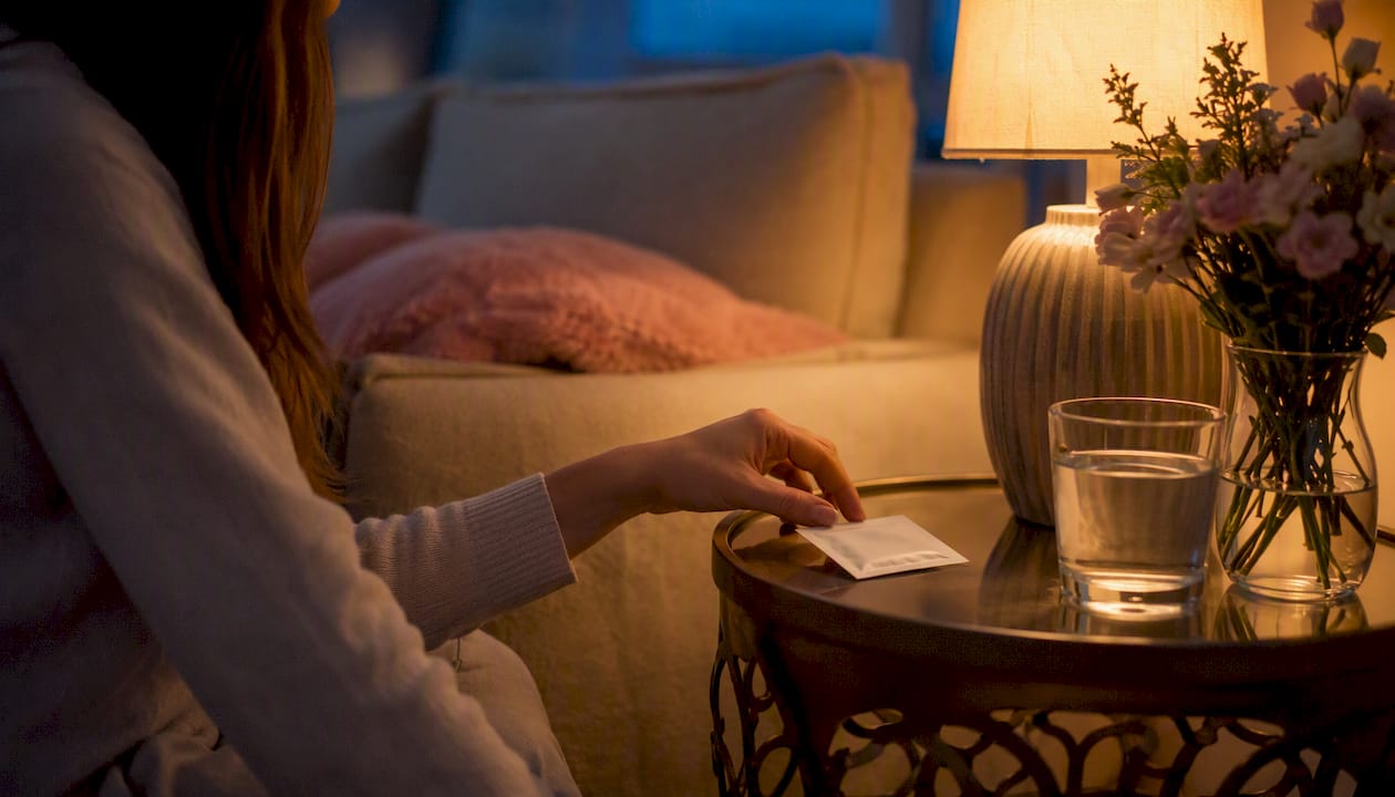 Hand reaching for oral strip on bedside table