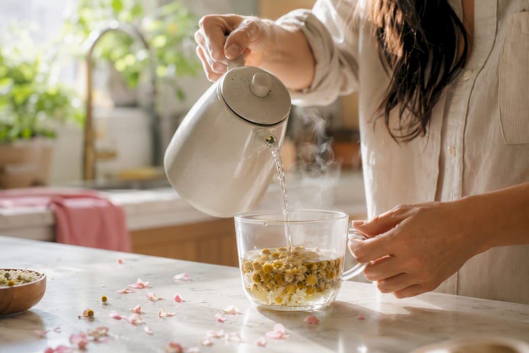Hands pouring herbal tea for hormonal balance