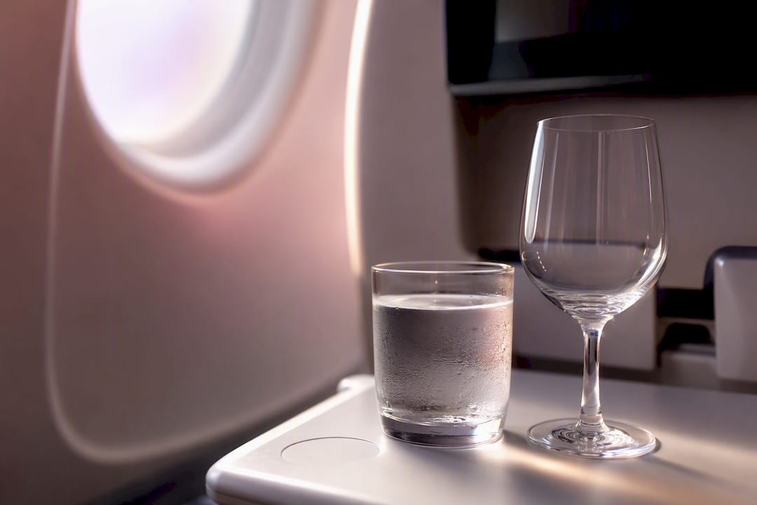 Water and wine glasses on airplane tray table