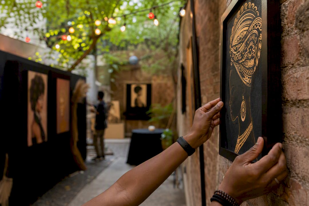 Artist hands hanging Black art at pop-up show