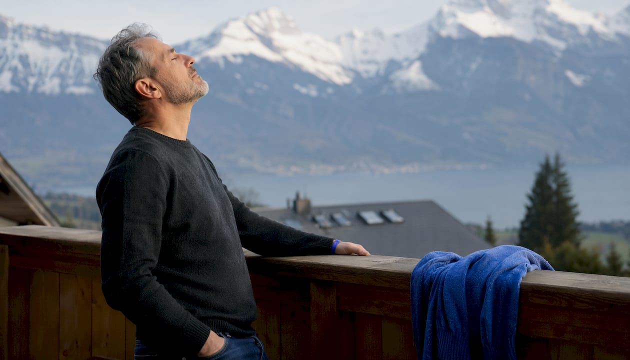 Ein Mann genießt eine entspannte Auszeit auf seinem Balkon.