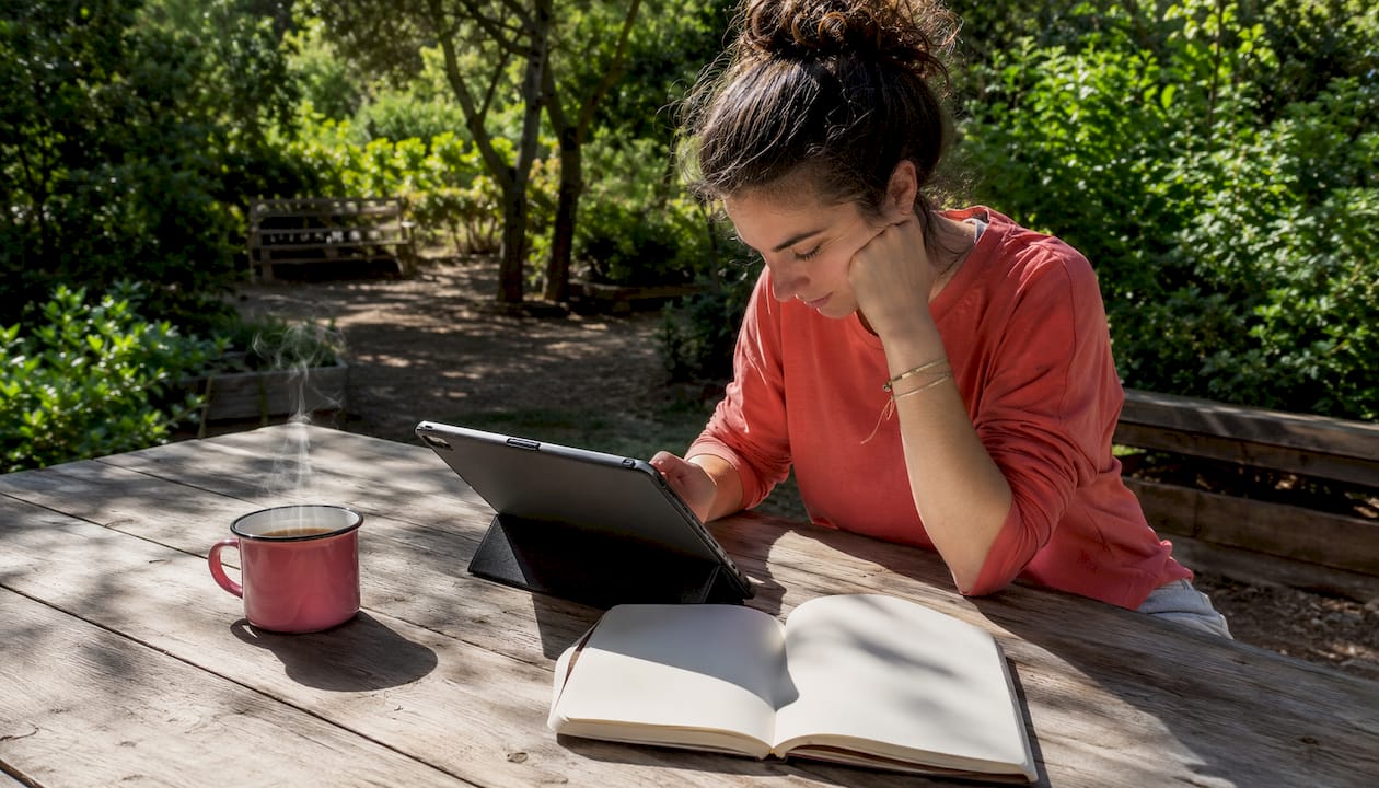 Une globe-trotteuse feuillette son guide numérique installée en terrasse