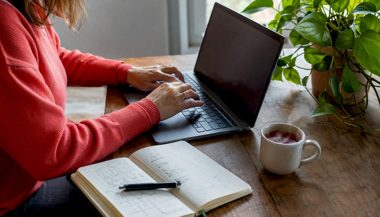 Une personne rédige un livret d'accueil personnalisé sur son ordinateur, en tapant sur le clavier.
