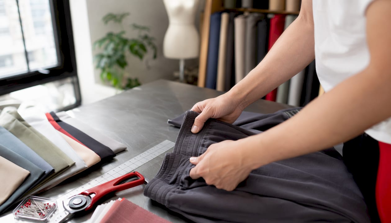 Hands displaying joggers waistband detail over fabric samples