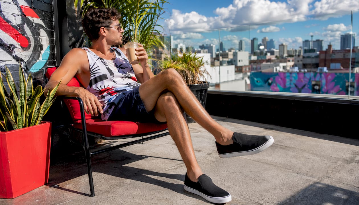 Man showcasing summer streetwear sneakers outdoors