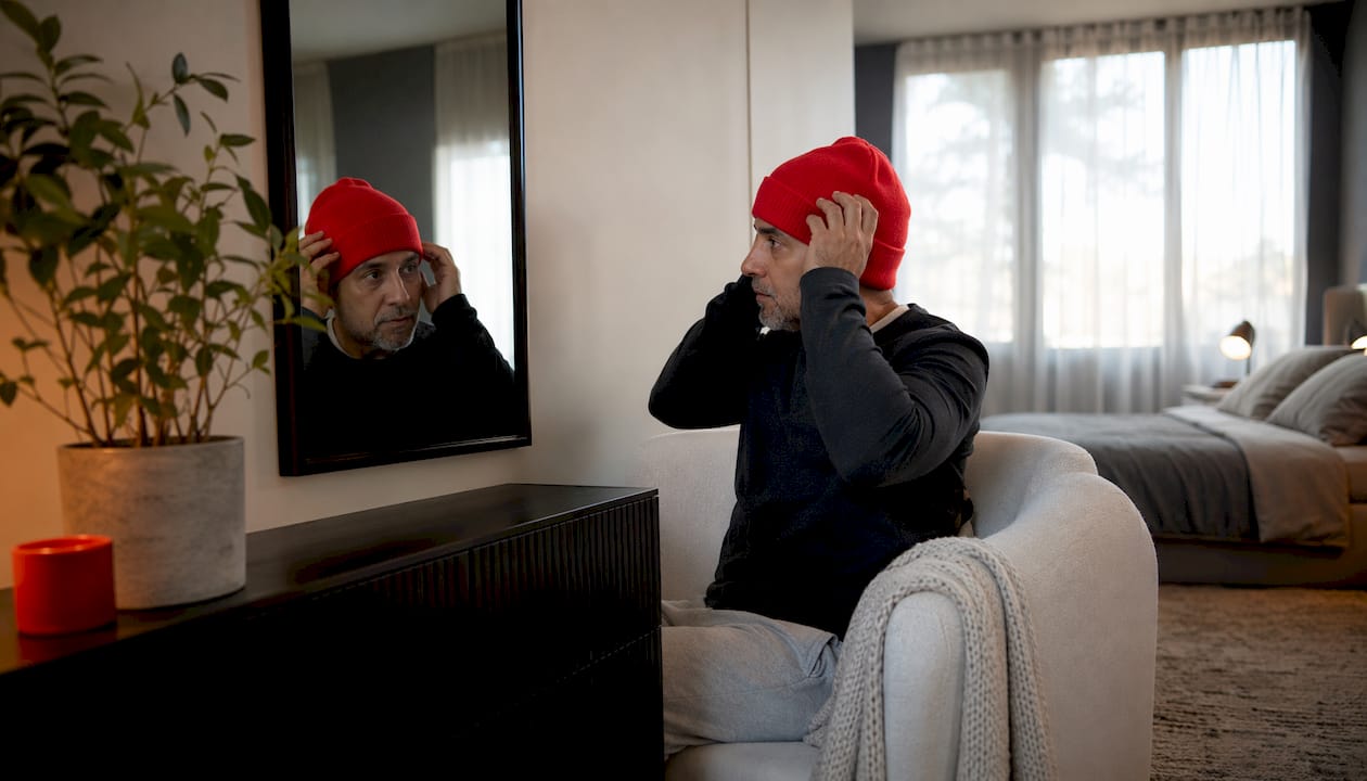 Man adjusting cashmere beanie indoors