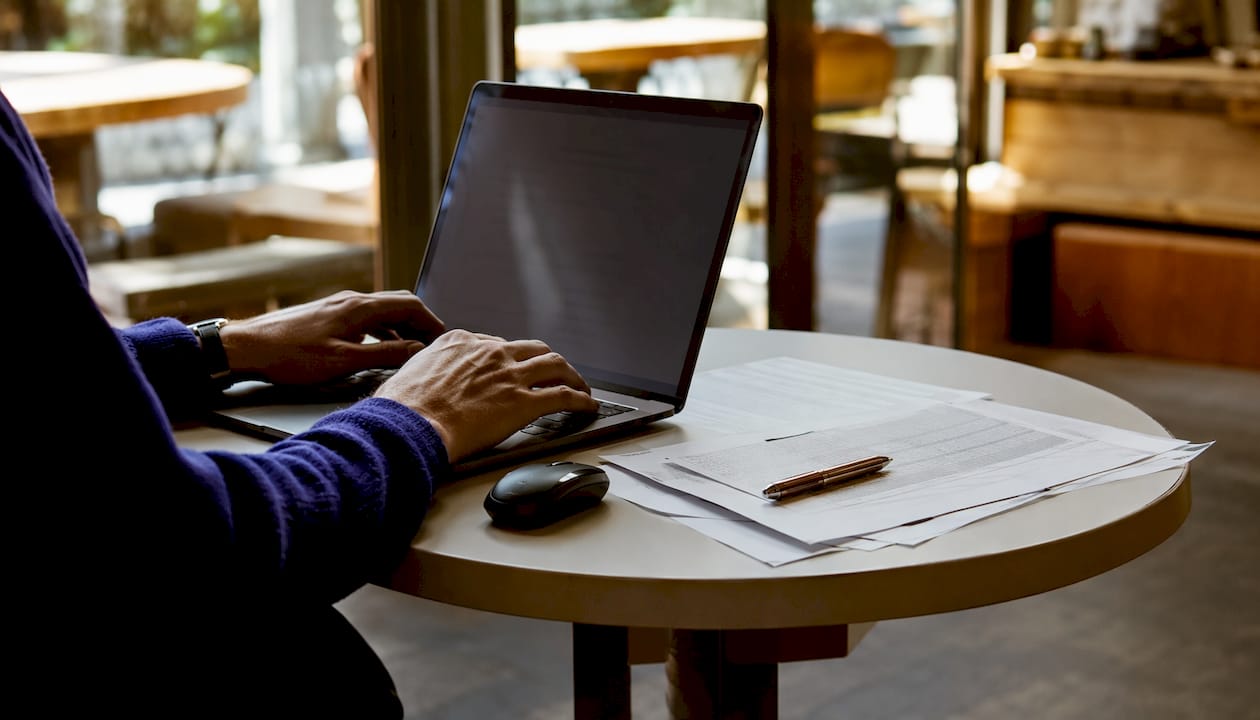 Hands typing on laptop using AI sourcing tools