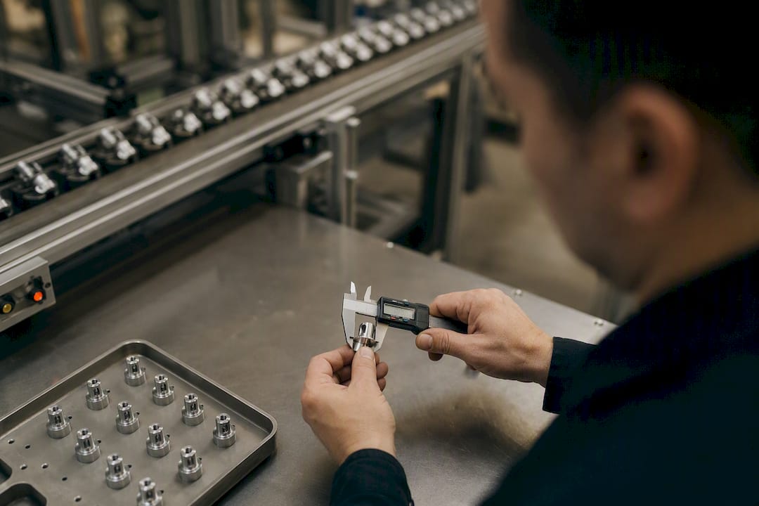 Inspector measuring factory part with caliper