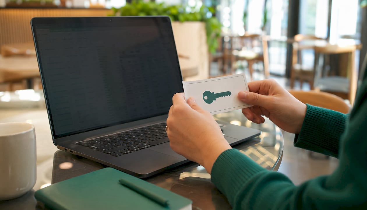Hands placing API key card next to laptop