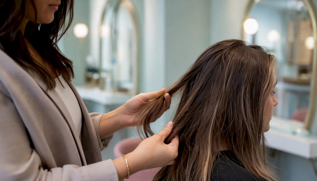 Stylist inspecting client's hair texture close-up