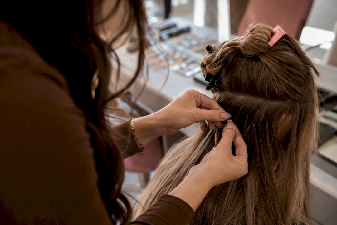 Stylist fitting nano bead extensions close-up