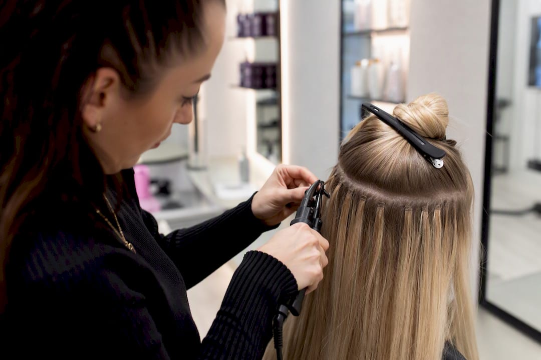 Stylist bonding u-tip hair extensions with heat