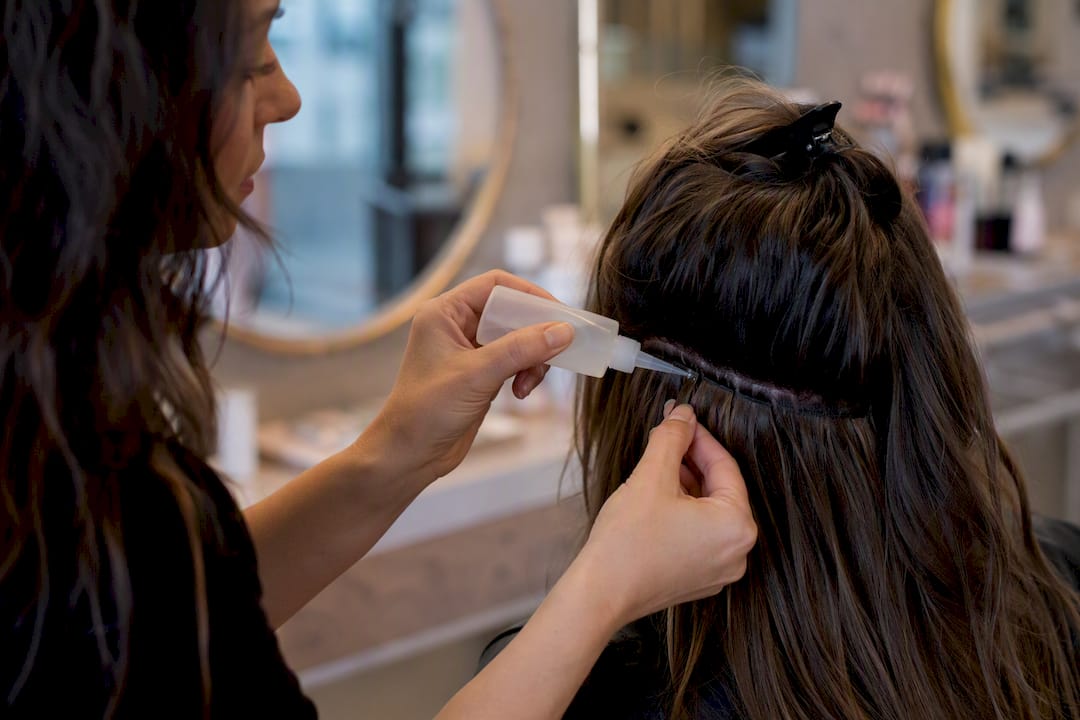 Stylist applying solvent to hot fusion keratin bond