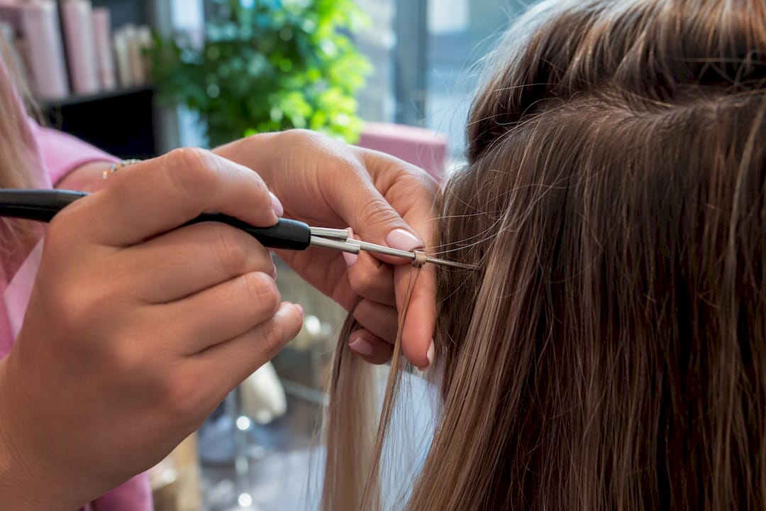 Hands applying cold fusion micro-bead extension