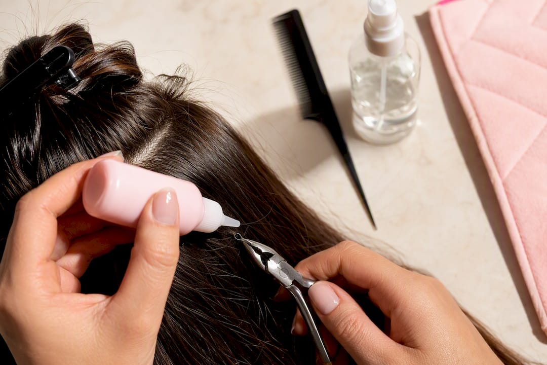 Hands applying detangler before bead removal