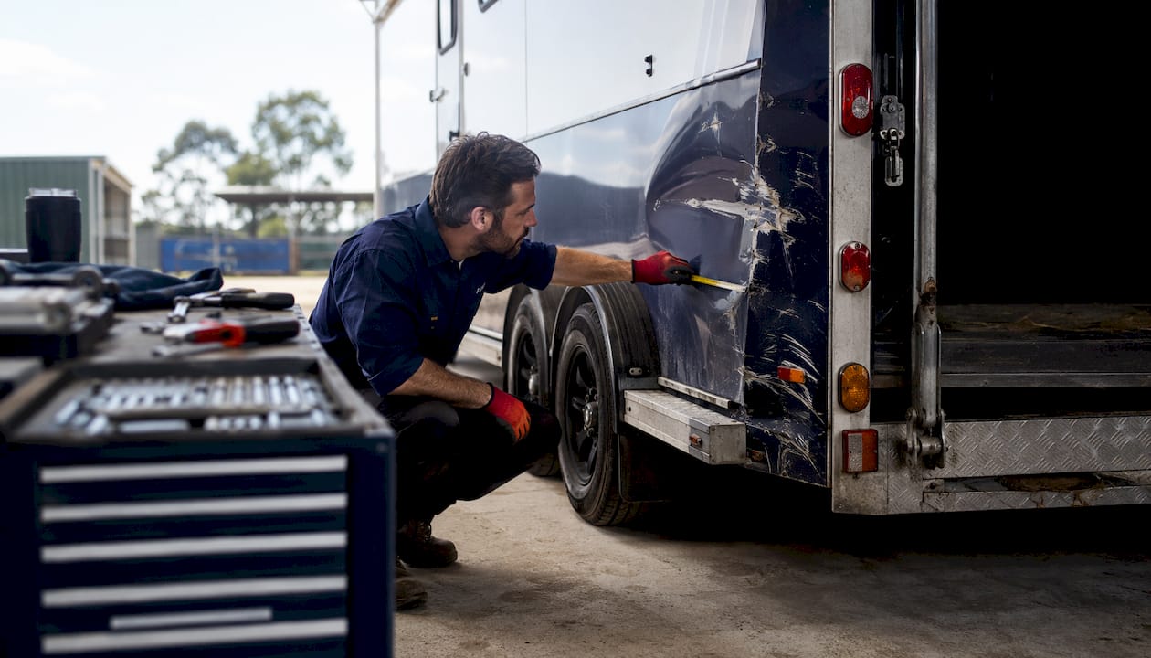 Mechanic inspecting damaged horse float trailer