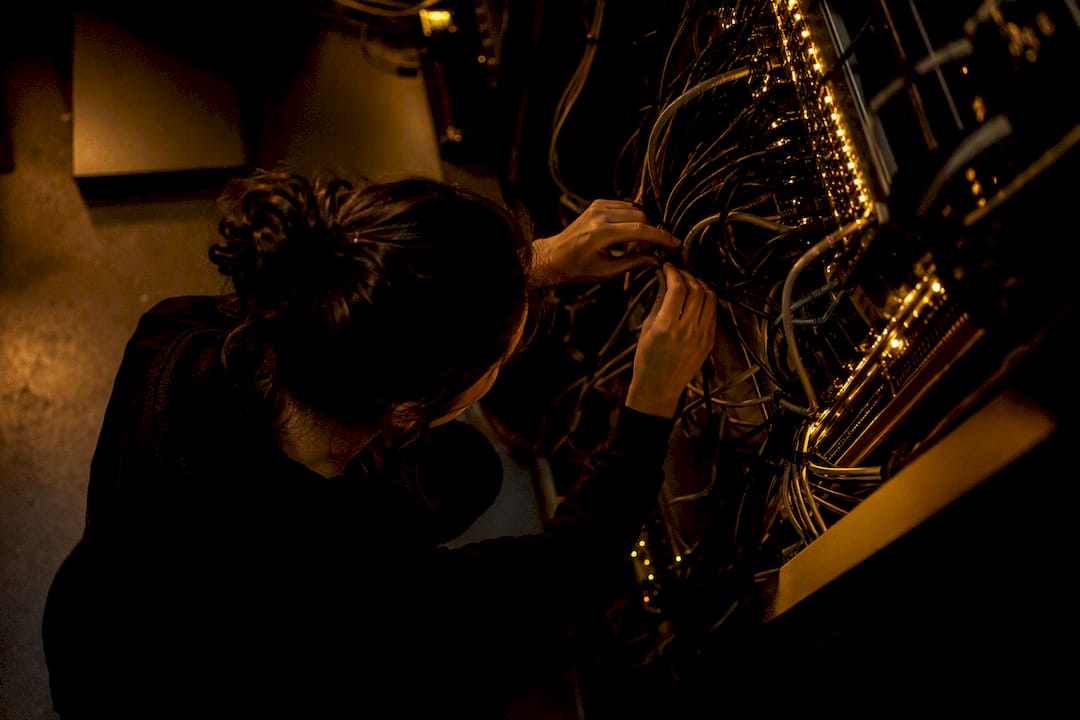 Hands connecting cables in dark tech server room