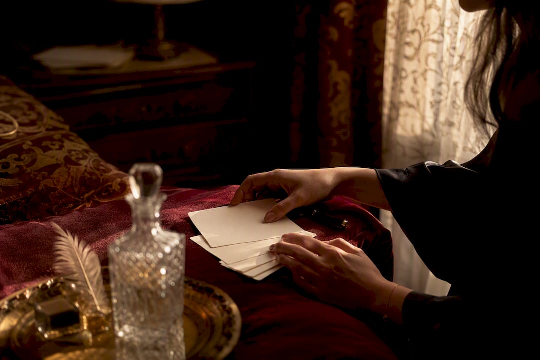 Hands writing BDSM scene notes in intimate room