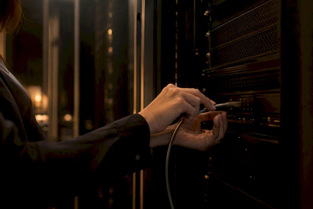 Hands connecting network cable in server rack