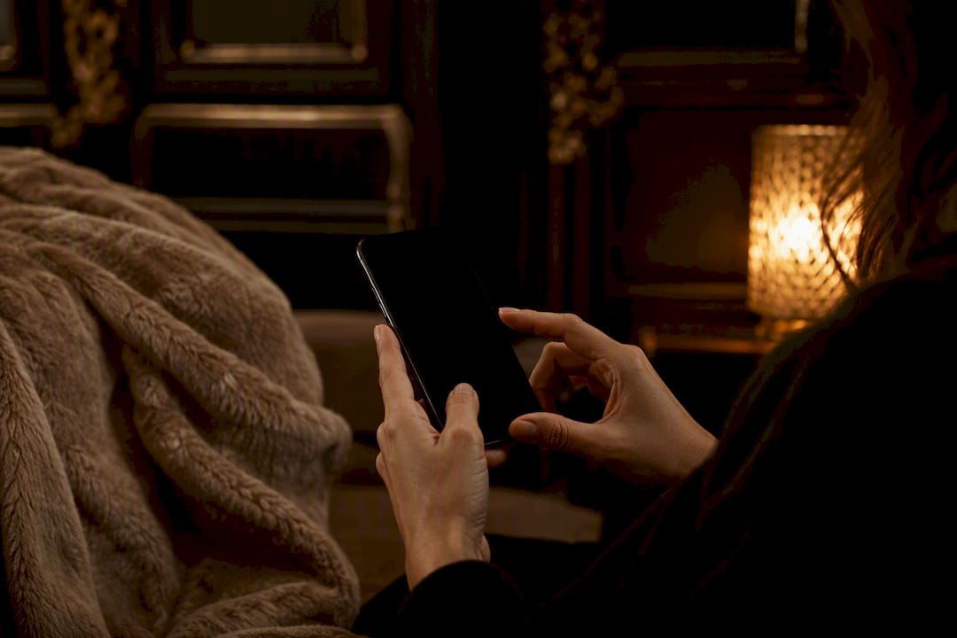 Hands holding smartphone with dark screen