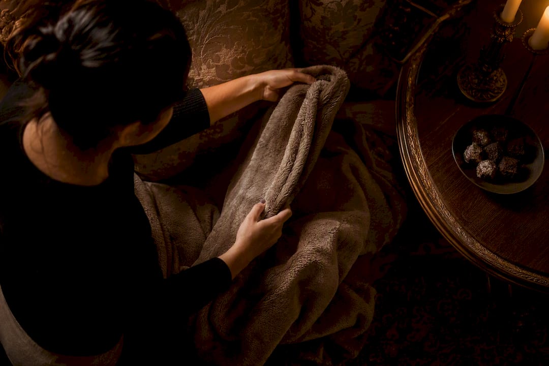 Hands arranging warm blanket and offering snack