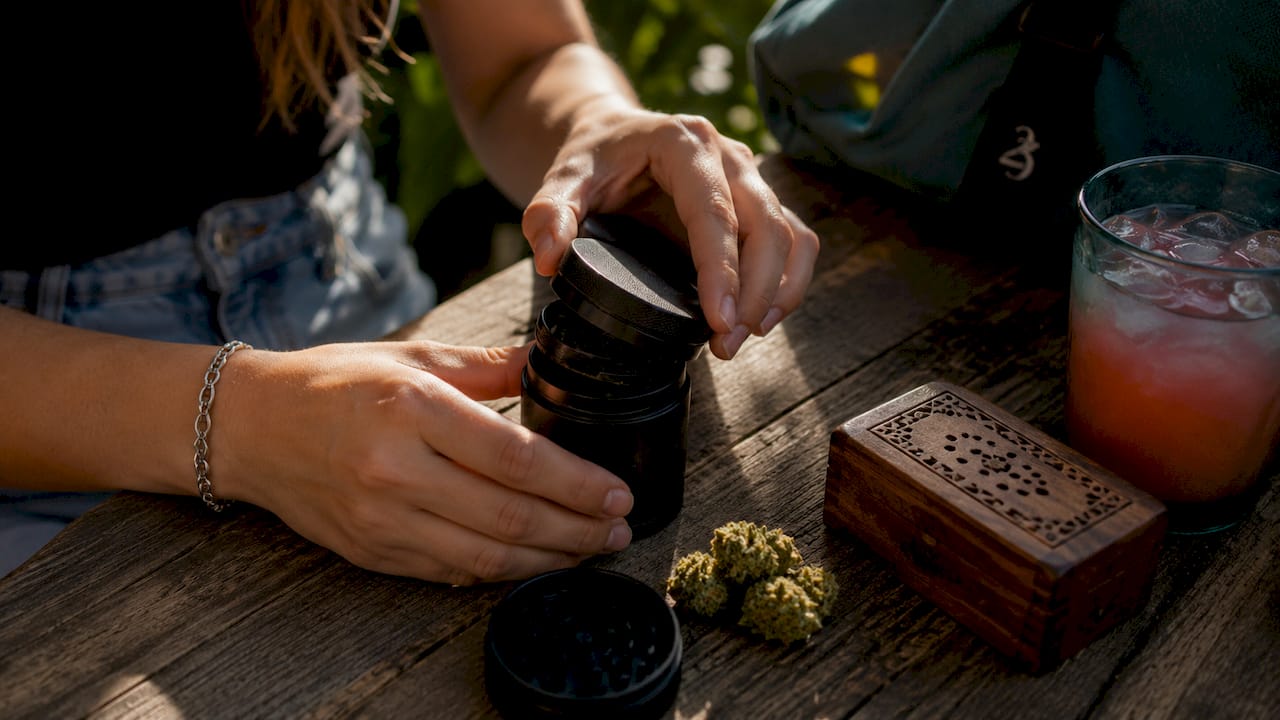 Hands opening cannabis grinder