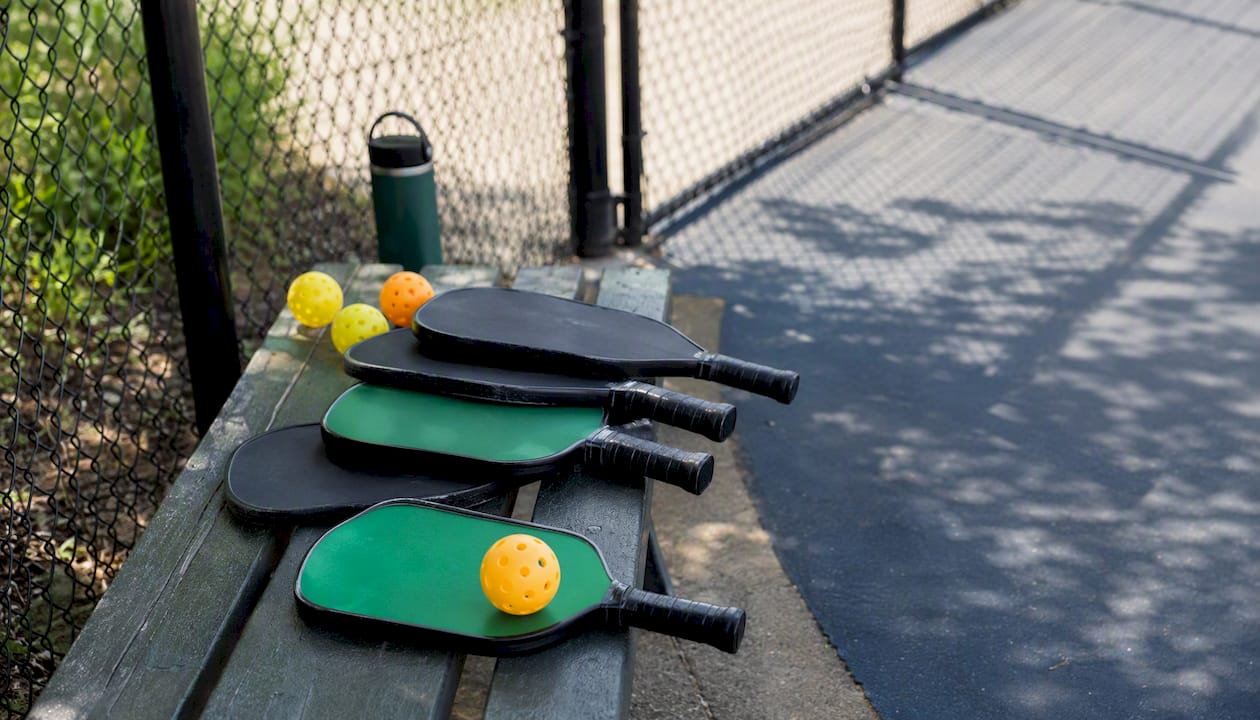 Pickleball paddles and balls on court bench