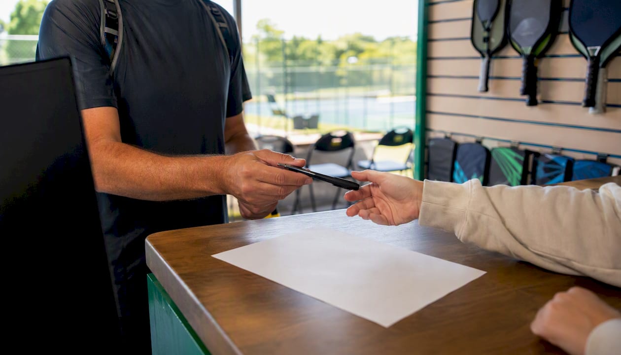 Volunteer physically signing form at pickleball desk