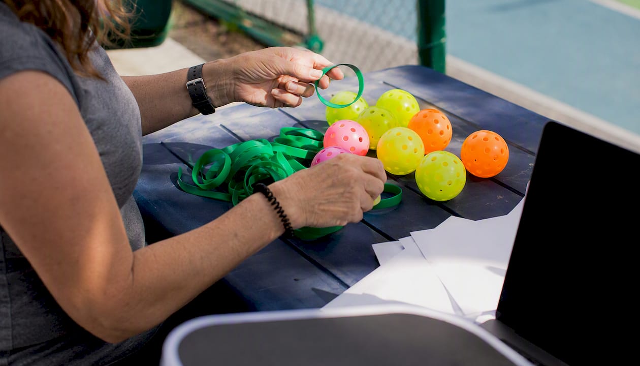 Volunteer arranging pickleball gear outdoors