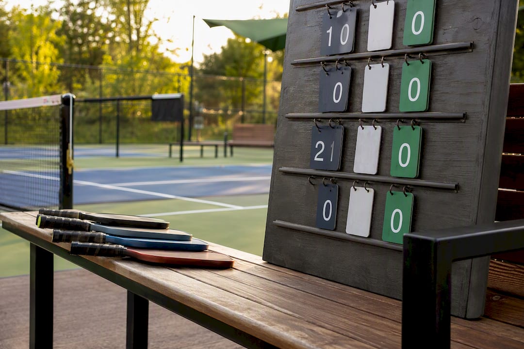 Scoreboard and paddles on pickleball court bench
