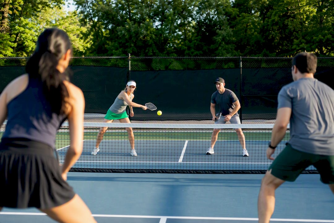 Four pickleball players volleying on outdoor court