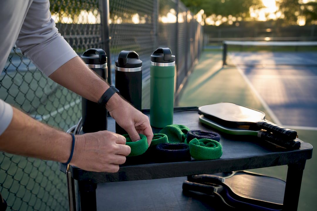 Hands arranging wristbands and water bottles on table