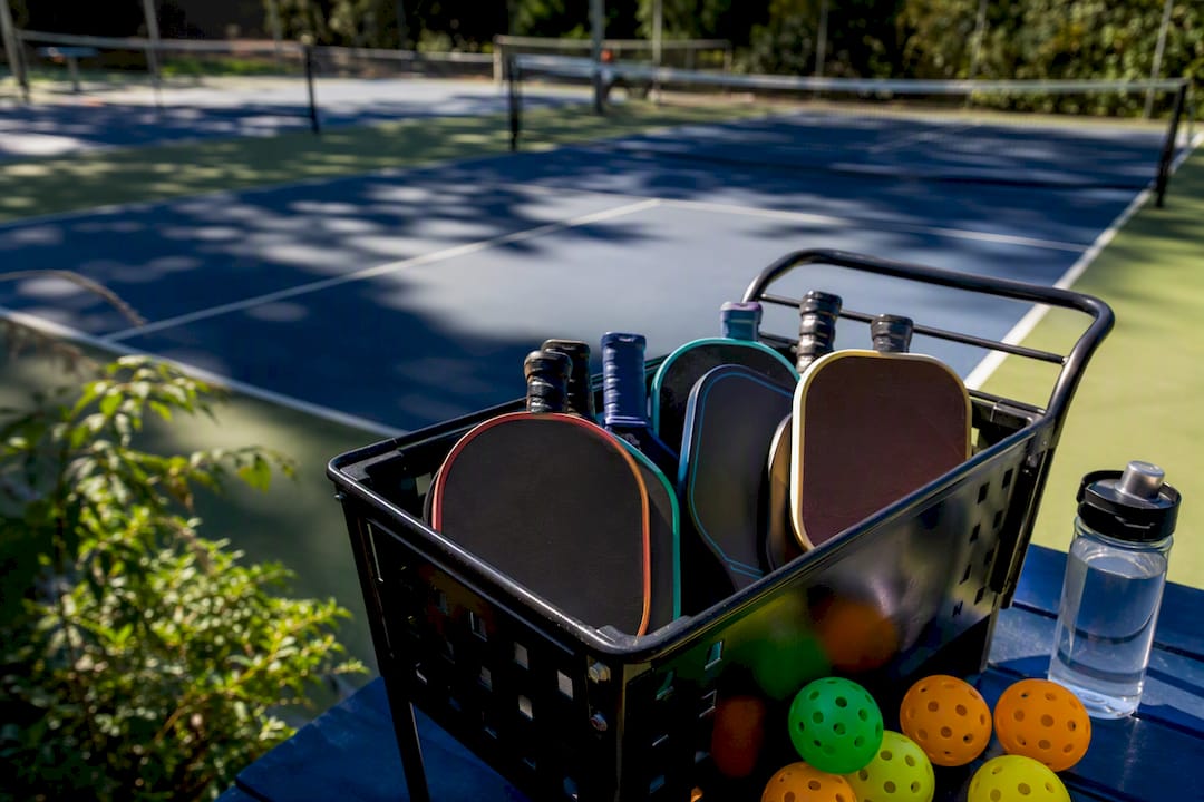 Pickleball paddles and balls on court bench