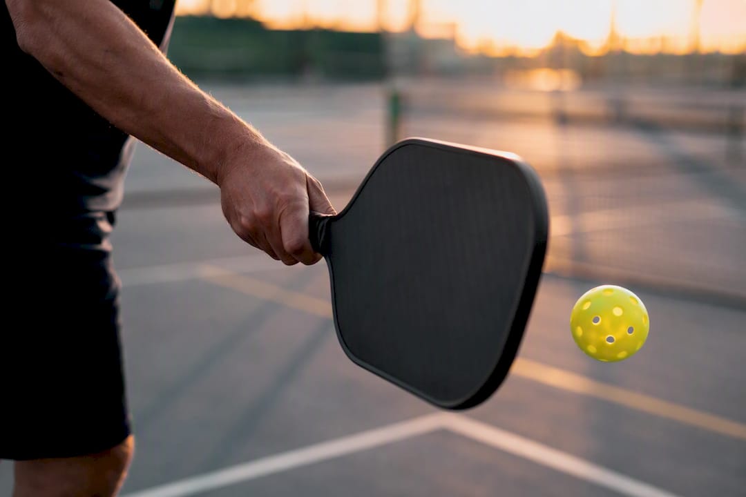 Pickleball player serving ball on court