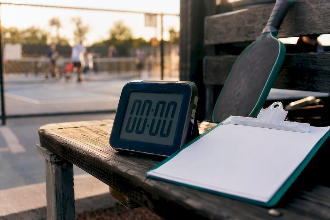 Stopwatch and clipboard near pickleball court bench