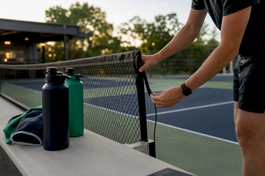 Hands setting up pickleball scoreboard on court