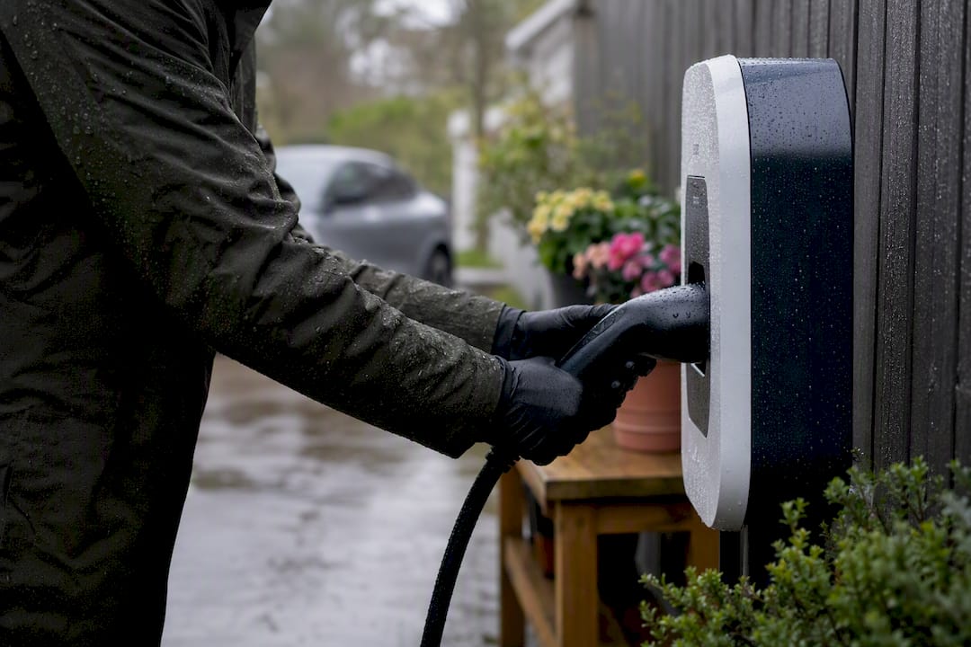 Hands plugging EV charger outdoors in rain