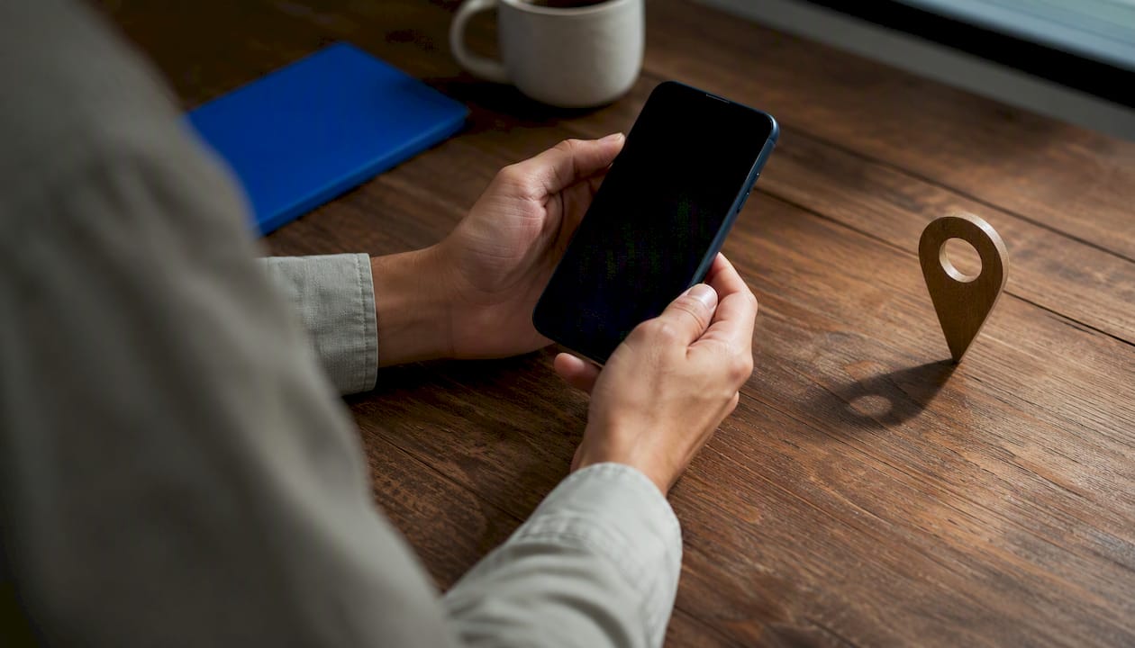 Hands holding smartphone with map pin shadow