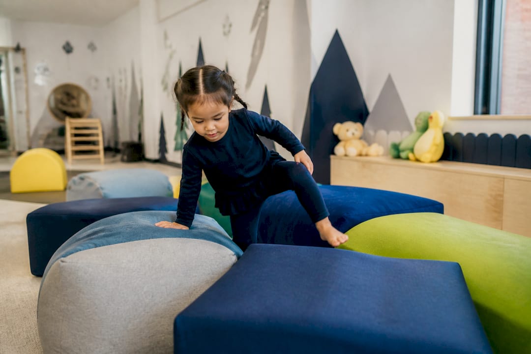 Child crawling under cushions in obstacle course