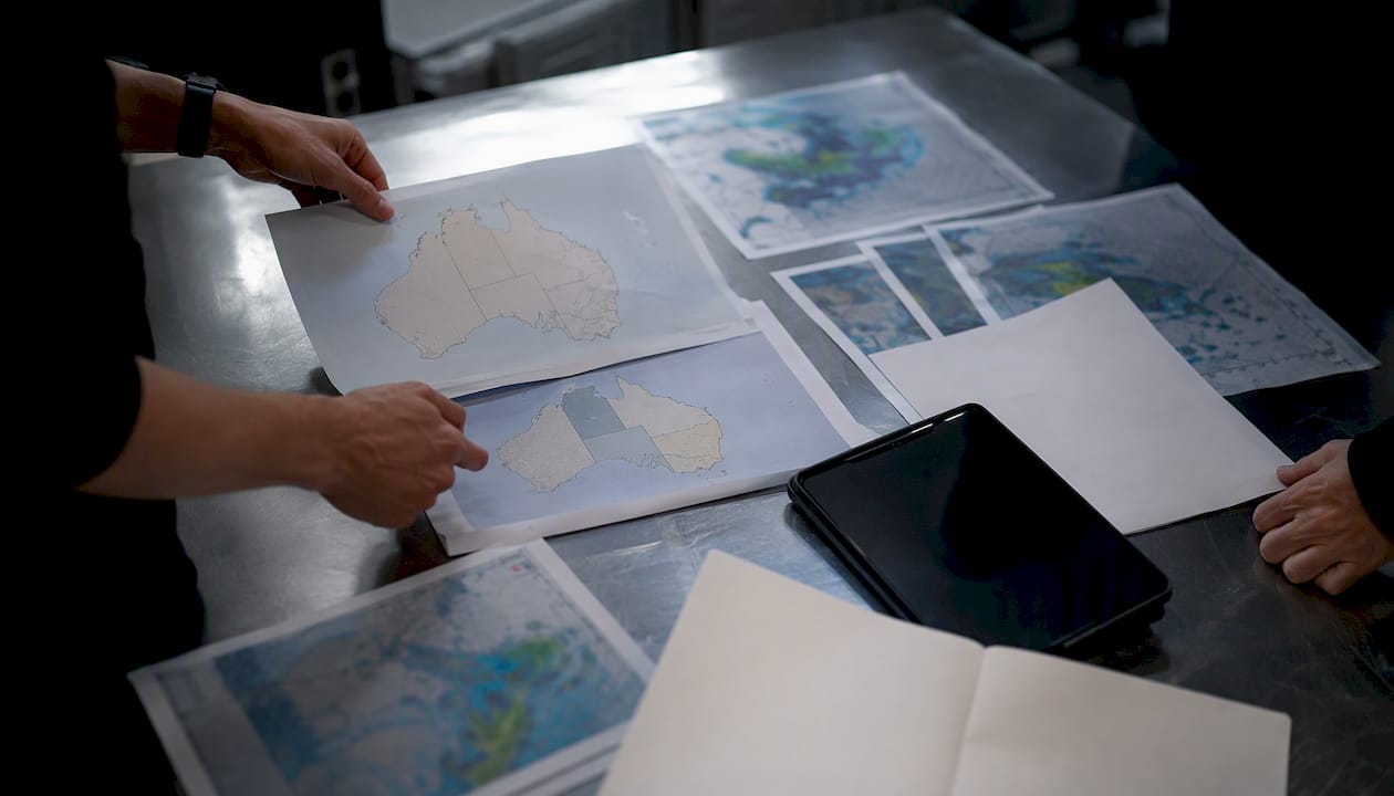 Hands arranging maps and tablet in supply chain audit