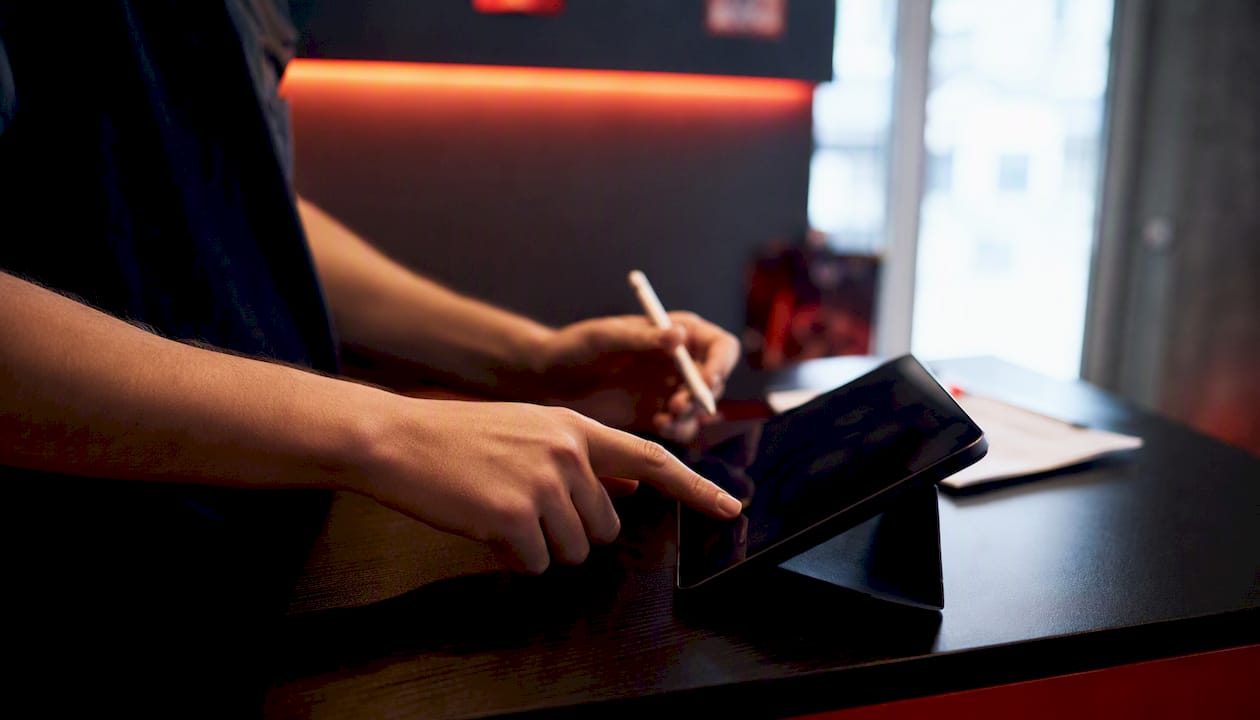 Hands linking digital waiver to booking on tablet