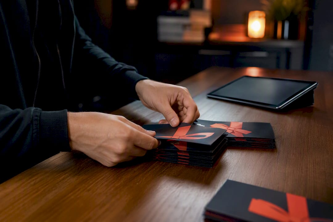 Hands organizing gift voucher tokens near tablet