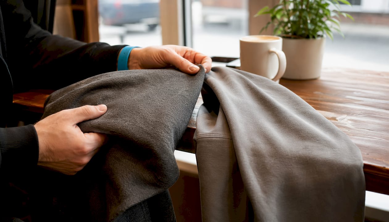 Hands comparing hoodie fabric textures closely