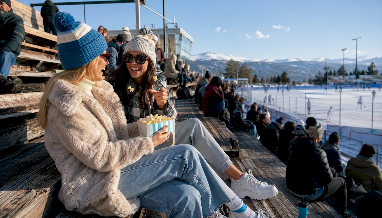 Two friends in warm hockey game outfits at rink