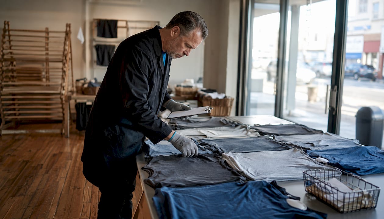 Quality specialist examining washed tri-blend and cotton shirts