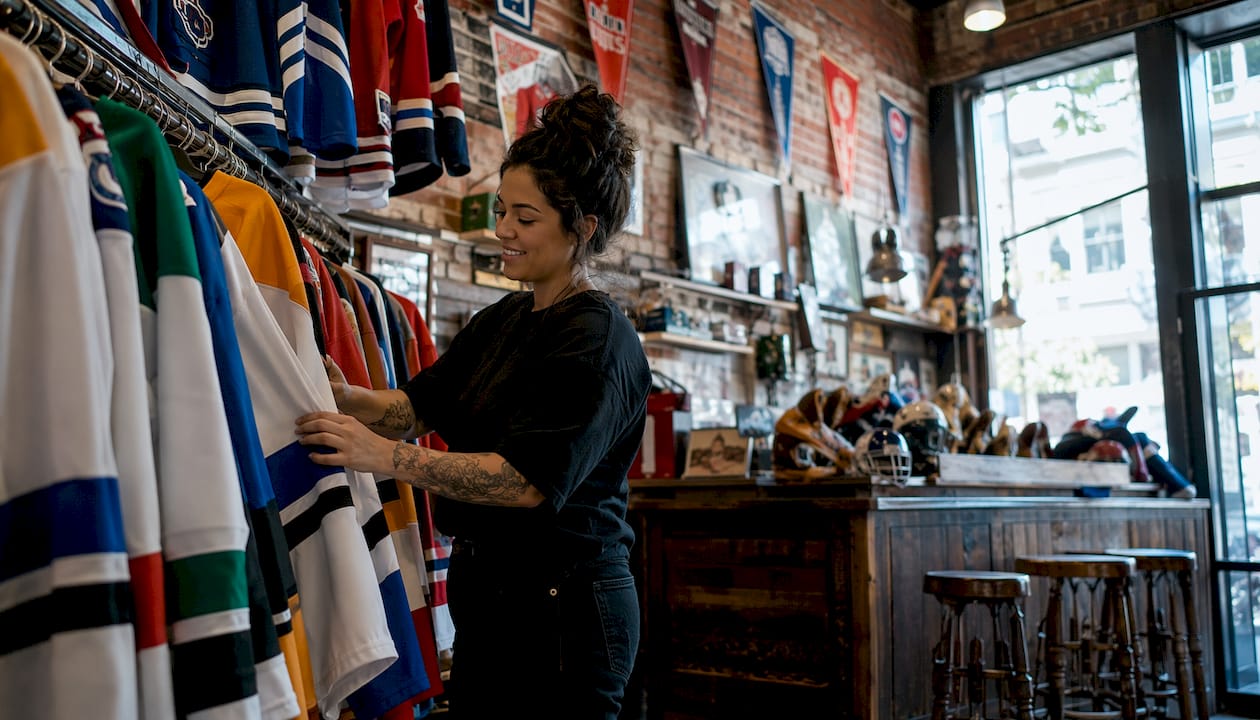 Vintage shop owner arranging hockey shirts on shelves