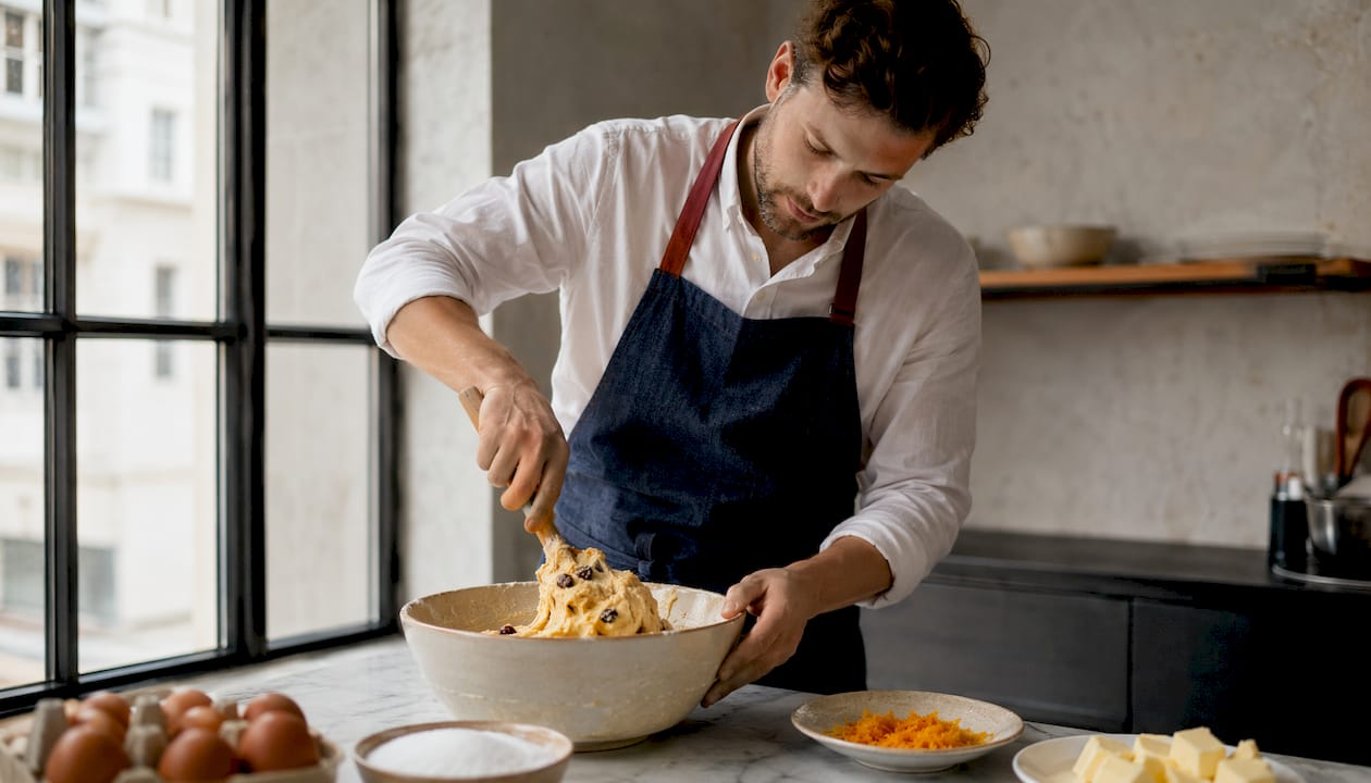 Un boulanger pétrit la pâte à la main dans une petite boulangerie artisanale.