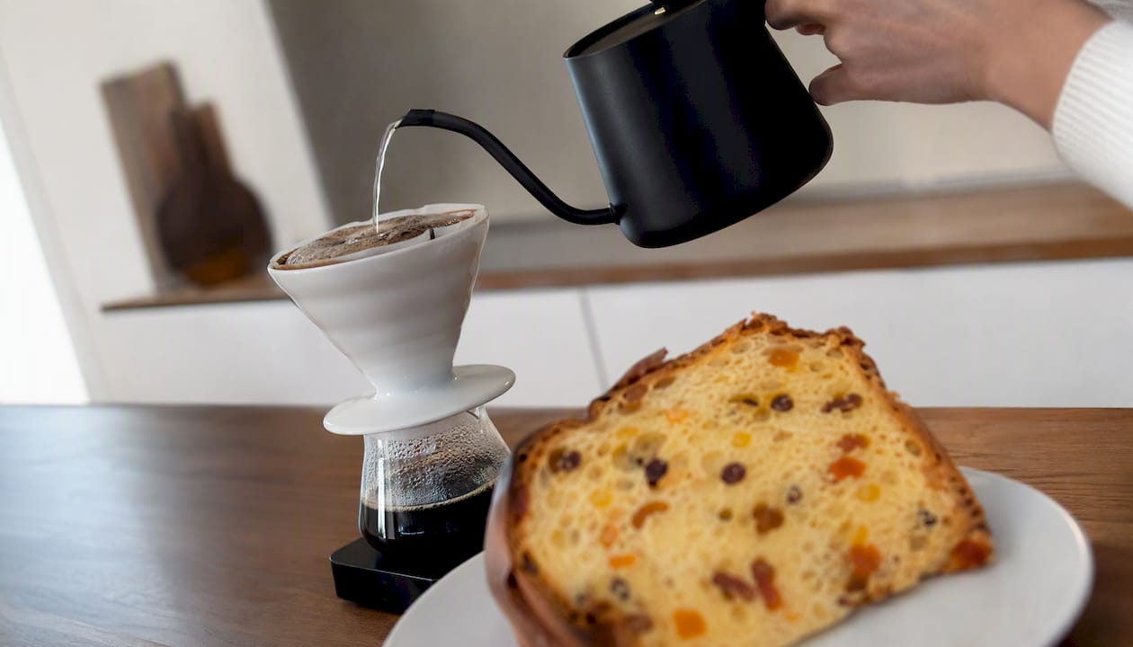 Un café filtre préparé à la main, servi à côté d’une tranche de panettone aux agrumes.