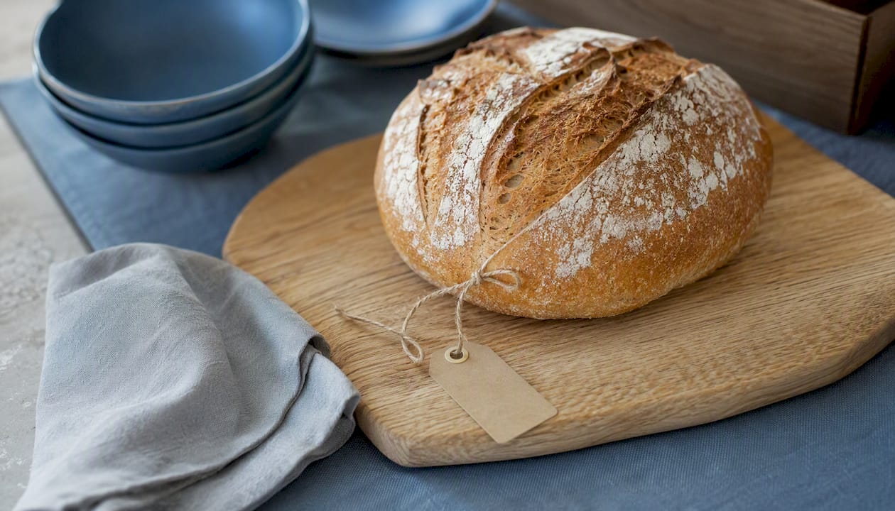 Pain au levain rustique présenté sur une planche en bois, idéal pour un buffet convivial.